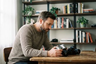 Homme pensif étudiant deux appareils photo en intérieur